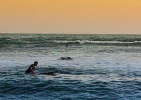Vibrant sunset scene of surfers riding waves in the open sea, capturing the essence of adventure and nature.